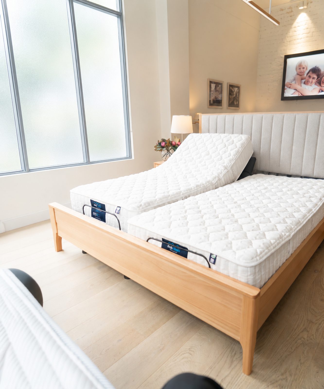 Split adjustable bed with one side raised in a bright showroom bedroom